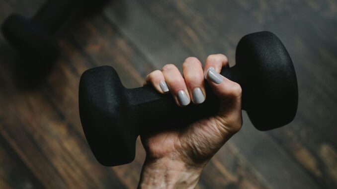 Person holding a dumbbell amid calls by IT professionals for stronger AI regulation, according to SolarWinds research.